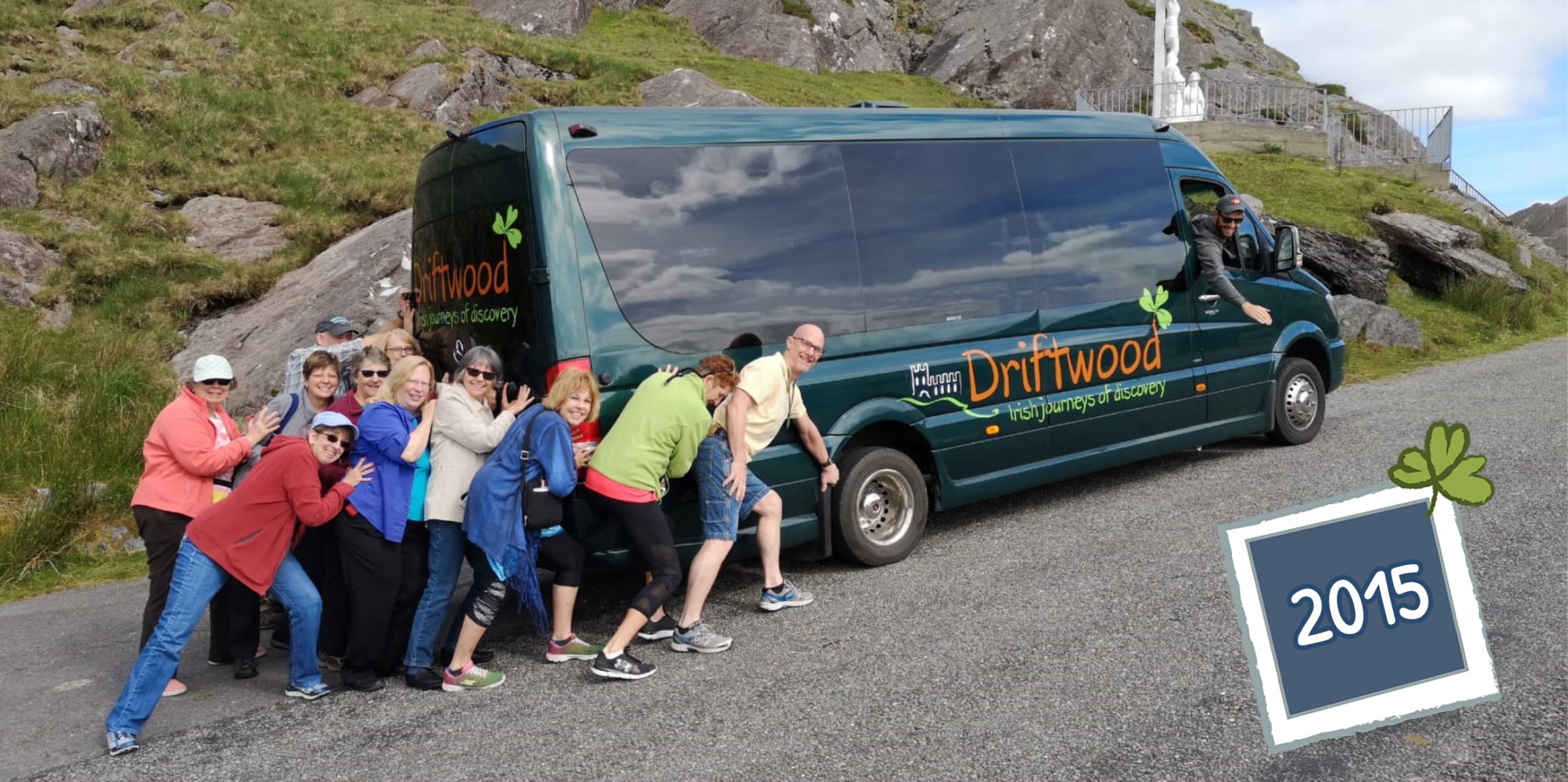A smiling group of Driftwood tour guests pranking around with a Drifter tour vehicle and guide