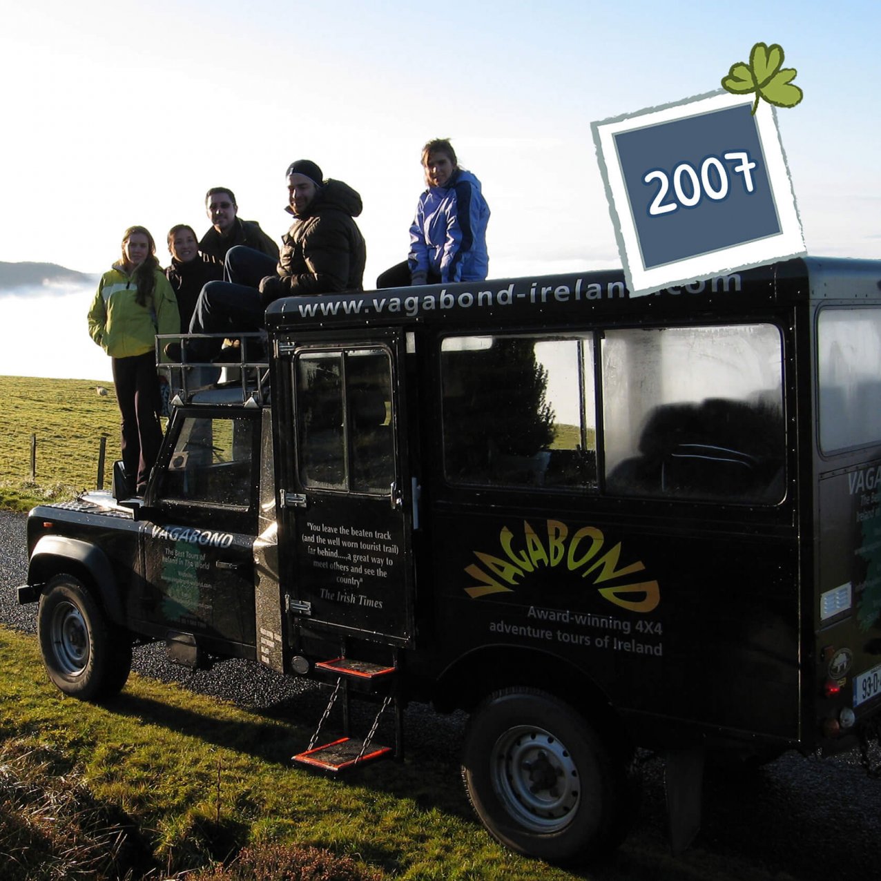 Vagabond Tours guest group sitting and standing on an original Land Rover Defender VagaTron tour vehicle with a 2007 date graphic in the top right corner