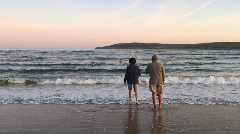 A couple watch two others swim in the sea in Donegal, Ireland
