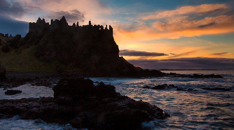 Silhouetted Dunluce Castle on the coast in Ireland