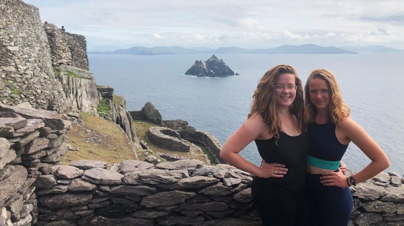 Two females near the summit of Skellig Michael with Little Skellig island in the background