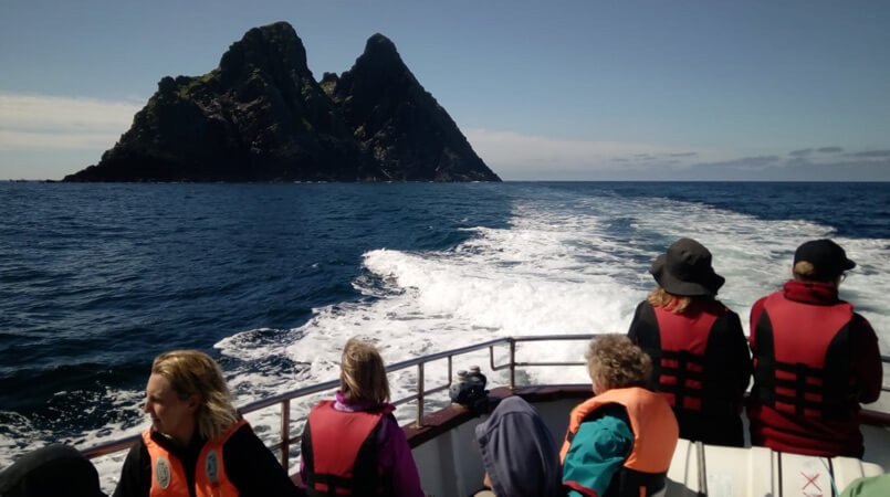 A group watch Skellig Michael island from a moving boat in Ireland
