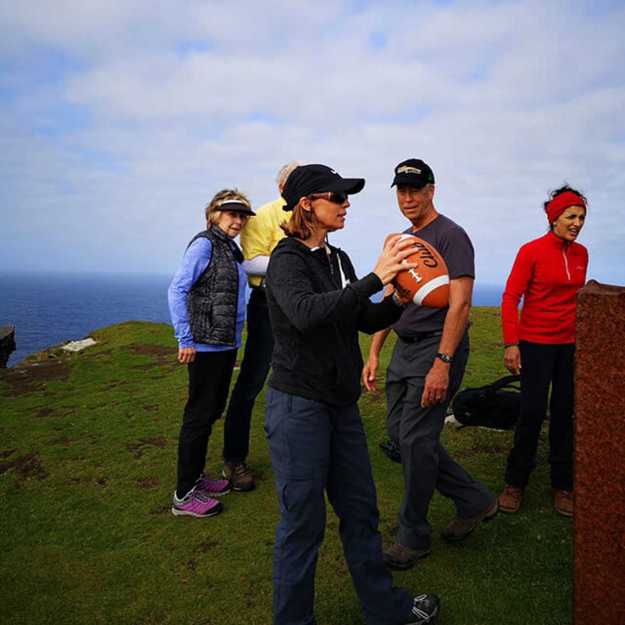 A group of guests on Bray Head with a woman at the front getting ready to throw an American football