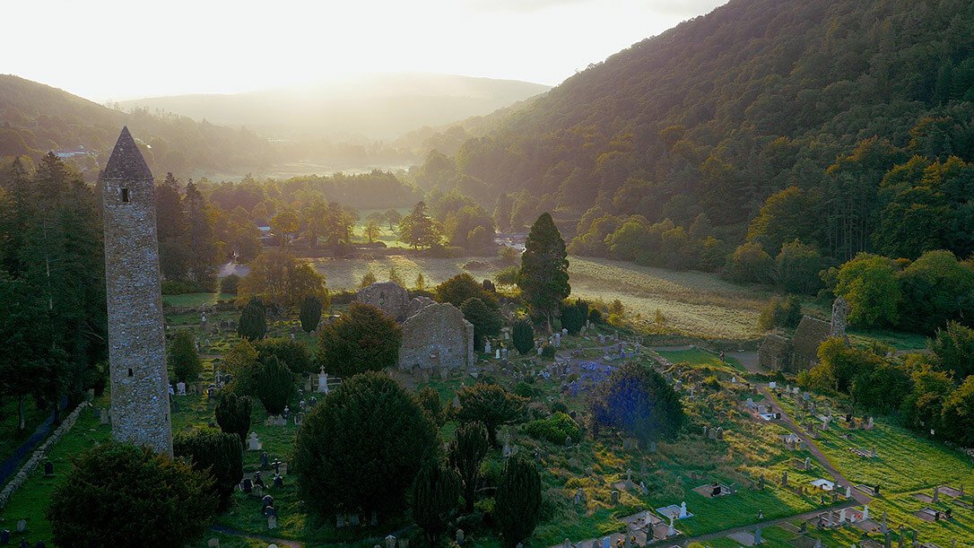 Aerial view of the ancient monastic city of Glendalough including a stone round tower, ruined church and graveyard