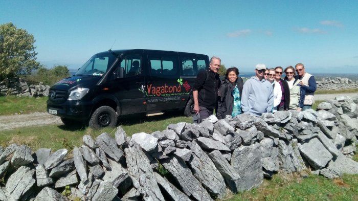 Vagabond tour group behind a dry stone wall with a VagaTron tour vehicle behind