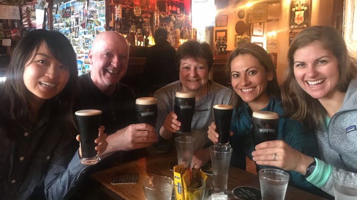 Five happy Vagabond tour guests toast the camera with pints of stout in a pub in Ireland - cheers!
