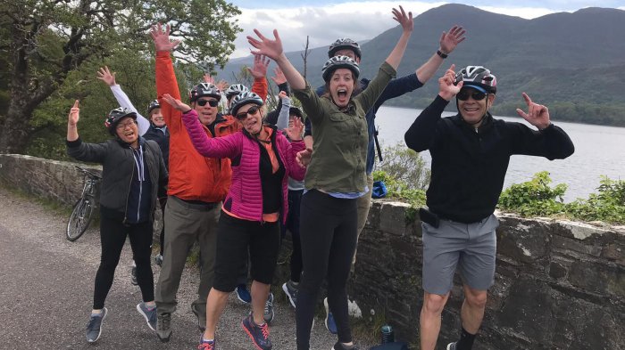 Happy Vagabond tour guests wearing cycling helmets and jumping in Ireland