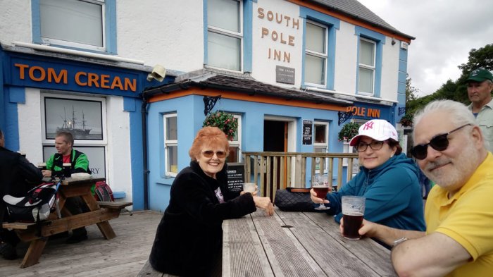Three people sitting outside the South Pole Inn enjoying a pint 